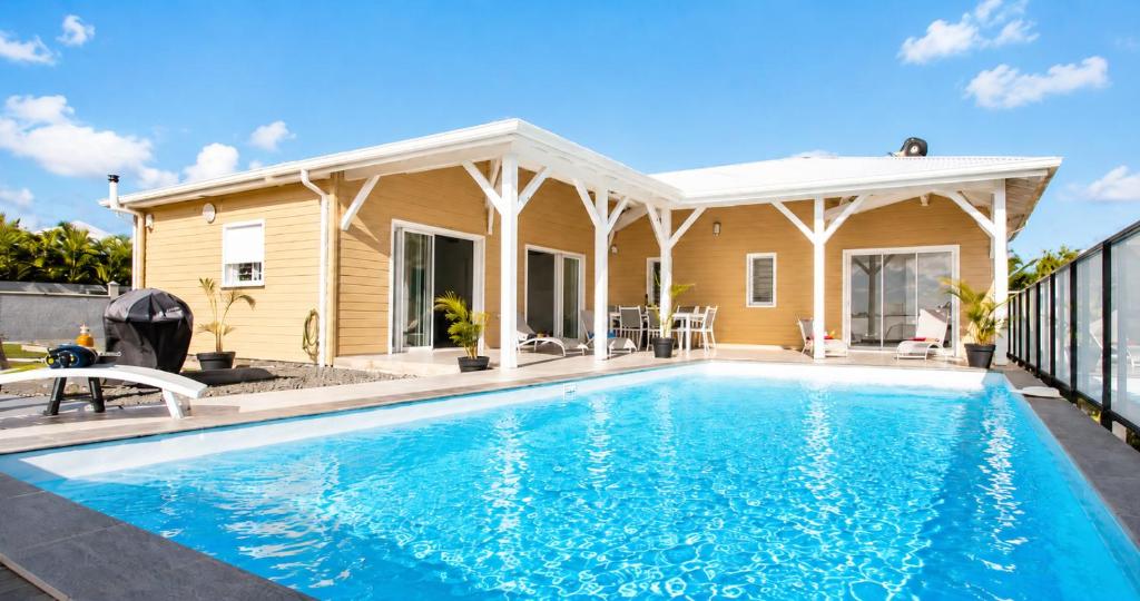 a house with a swimming pool in front of a house at Villa Noyanny Piscine Privée Calme in Le Moule