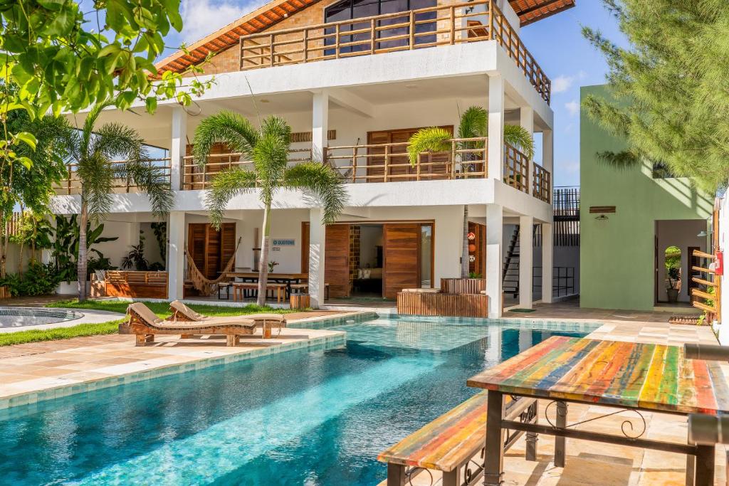 a villa with a swimming pool and a house at GreenHousi Boutique Preá in Prea