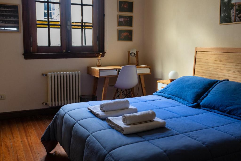 a bedroom with a blue bed with towels on it at Planta Alta Bed & Breakfast in Buenos Aires