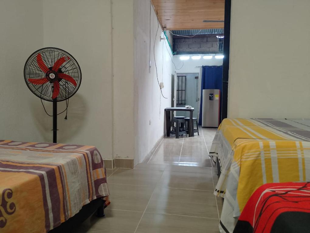 a room with two beds and a fan on the wall at Raíces del Obrero in Honda