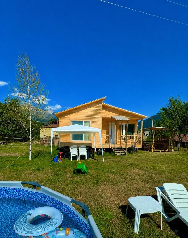 a house with a yard with a pool and chairs at HOMELAND in Mestia