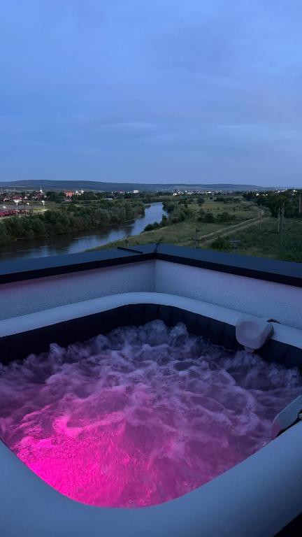 a hot tub filled with pink water next to a river at River View Penthouse & Jacuzzi in Reghin