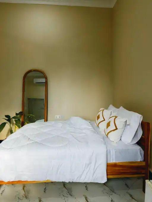 a bedroom with a white bed with a mirror at Rocky Apartment Zanzibar in Zanzibar City