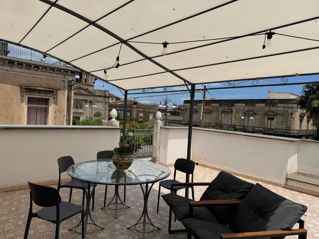 a patio with a glass table and chairs at House S&D in Giarre