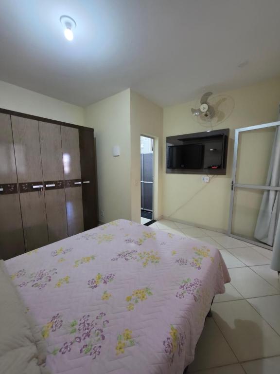a bedroom with a large bed with a pink blanket at Suíte independente com cozinha e varanda in Piúma
