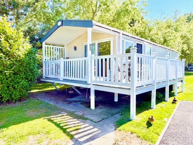 a small house with a white deck on the grass at Luxury 2 Bed Caravan With Decking - Sleeps 4 - at Broadland Sands Park in Lowestoft