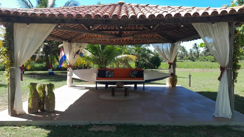 an outdoor pavilion with a table and a bench at Chácara Amsterdam in Aracaju