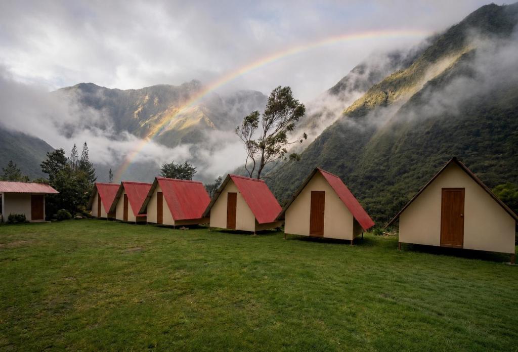 a row of houses with a rainbow in the mountains at Refugio Salkantay collpapampa in Colcapampa