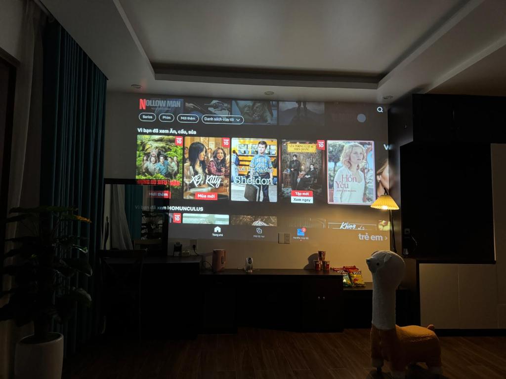a room with a large screen with many pictures on it at 05 Homestay Cinema in An Khê