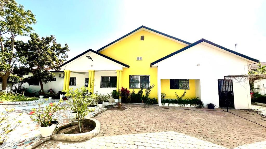 a yellow and white house with a brick driveway at B & B Villa Calliandra in Bijilo