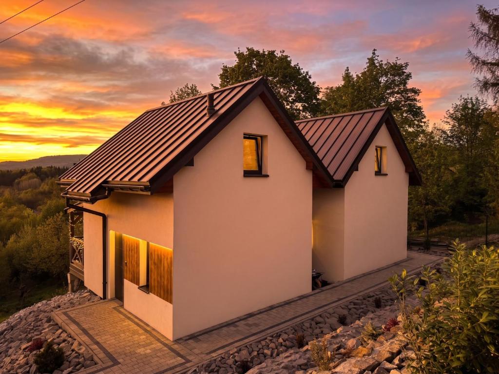 a house on a hill with a sunset in the background at Osada ŁYSKA in Żywiec