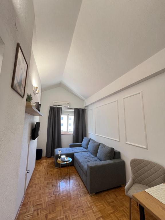 a living room with a blue couch and a table at Apartmani MM Trebinje in Trebinje