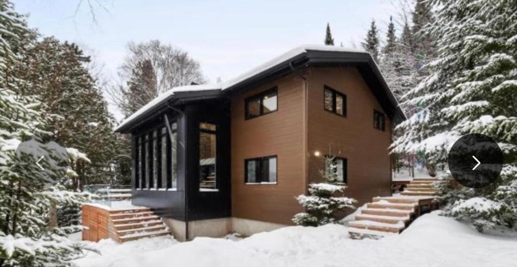 a house in the snow with snow covered trees at Chalet ouareau in Saint-Donat-de-Montcalm