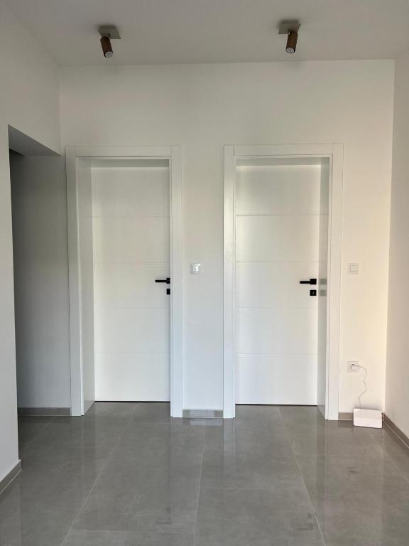 three white doors in a room with a tile floor at Guest House Gabi in Srima
