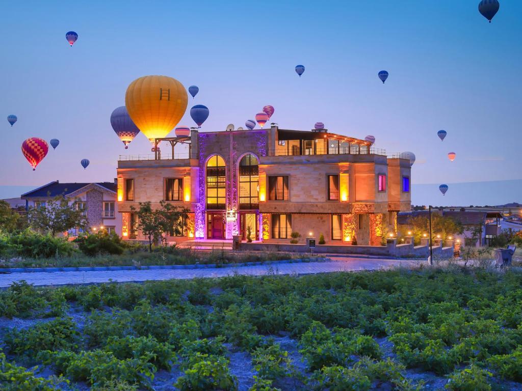 a building with lots of hot air balloons in the sky at Noble Crown Stone House Cappadocia in Uçhisar