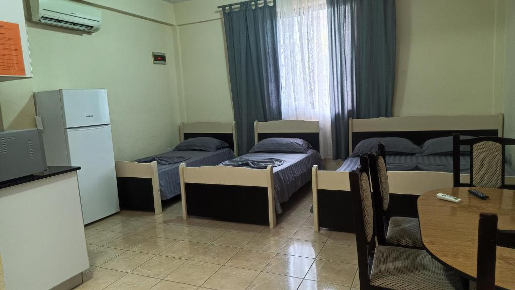 a room with three beds and a table and a kitchen at ℰ`ℋ Hotel - Velipoje rruga nr 7 in Velipojë