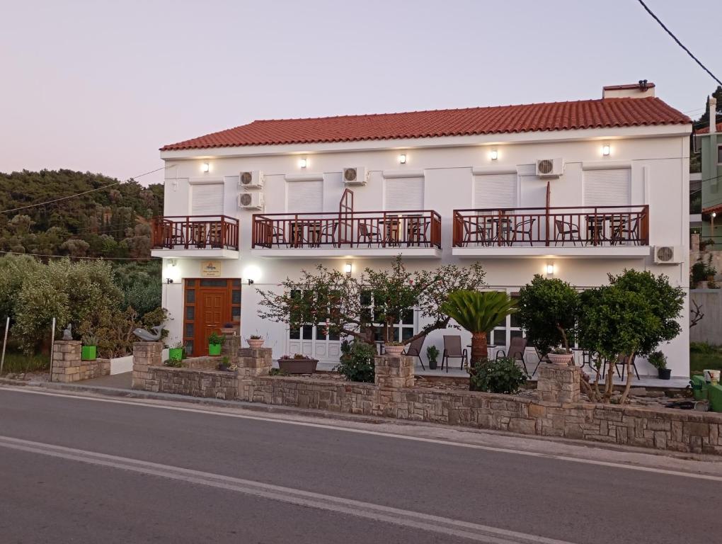 a white house with a balcony on a street at Dina Apartments Kokkari, Pension Dina, Dina Rooms in Kokkari