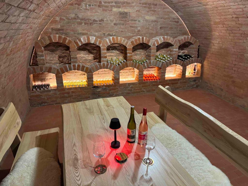 a table with wine bottles and wine glasses on it at Apartmán Sebina s vinným sklípkem in Drnholec