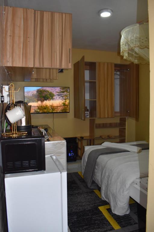 a bedroom with a bed and a desk with a microwave at Unique place Studio Thika in Thika