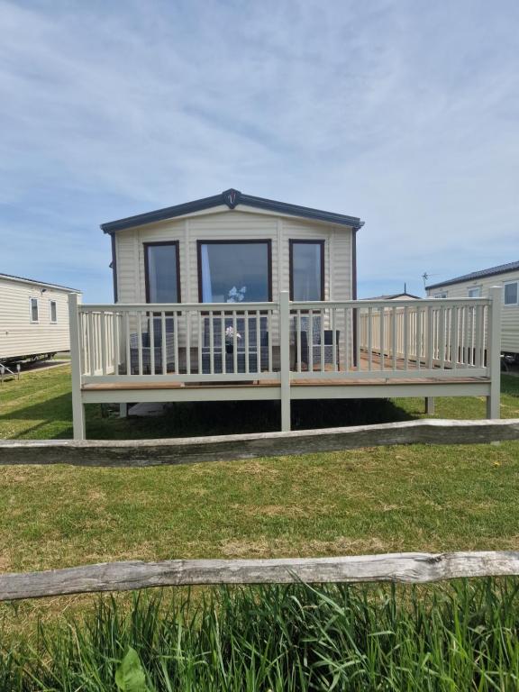 a tiny house with a porch and a deck at Riley's Caravan sand le mere tunstall view in Tunstall