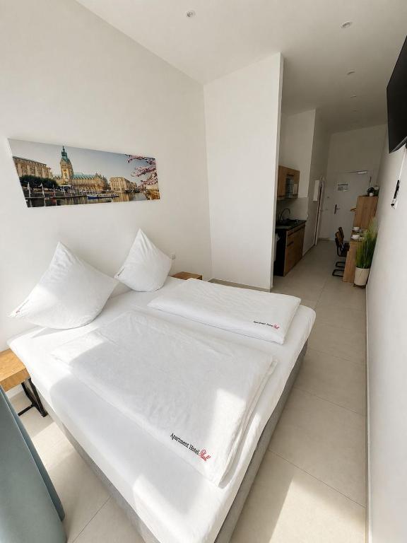 a white bed in a room with a picture on the wall at ApartHotel Rahl in Hamburg