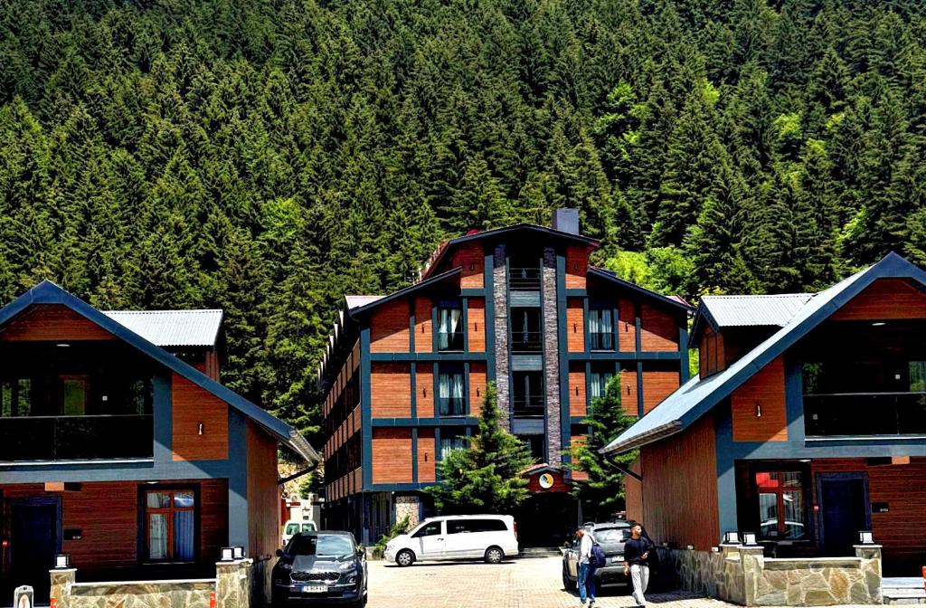 a large building with cars parked in front of a mountain at Sezgin Hotel in Uzungöl