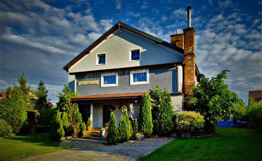 a house with a gambrel roof with bushes and trees at Dom Rybaka Bobolin in Bobolin