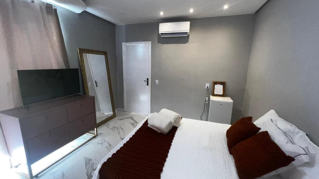 a bedroom with a bed with a television and a mirror at Flat no Centro da Cidade in Parauapebas