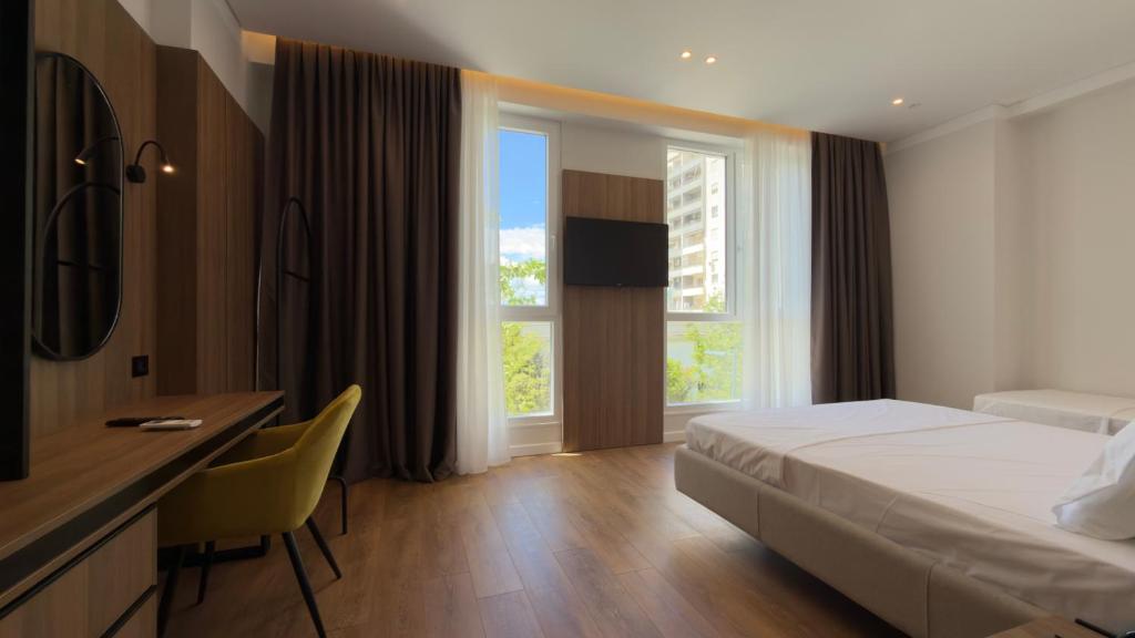 a hotel room with a bed and a desk and a window at Art Hotel Vlora in Vlorë