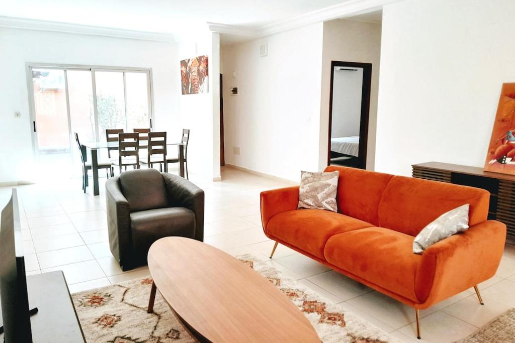 a living room with an orange couch and a table at Villa Terracotta - Riviera Synacassi - 3 chambres in Abidjan