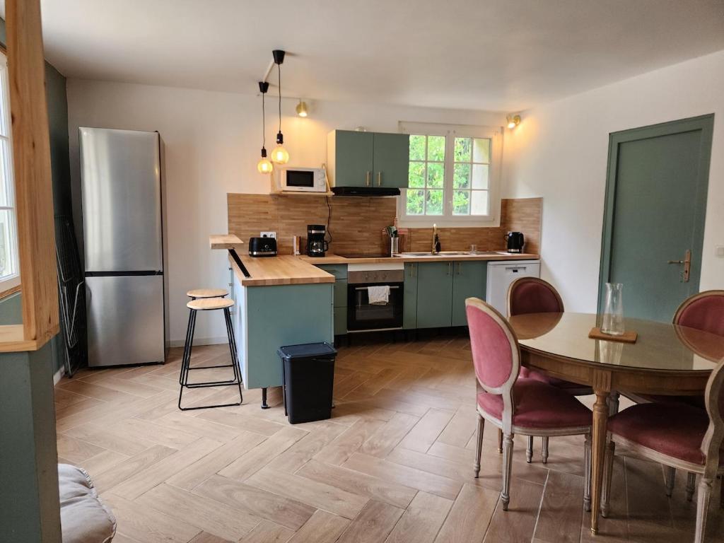 a kitchen with a table and a refrigerator at La Pastellière - Combrand in Combrand