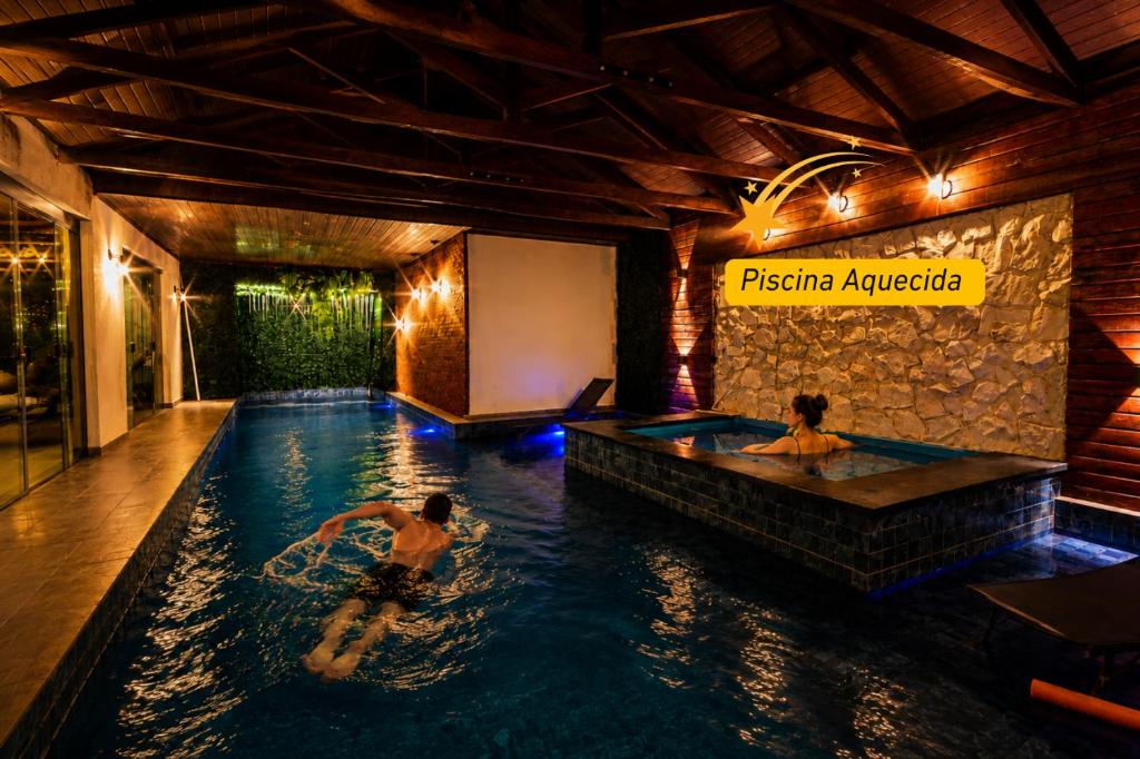 two people in a swimming pool at a hotel at Pousada Chale Luiz in Santo Antônio do Pinhal