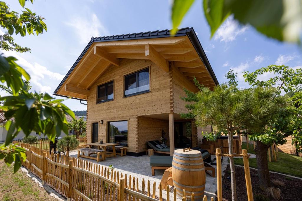 a house with a wooden fence and a barrel at Bayerwald Chalet Liebenstein in Bad Koetzting