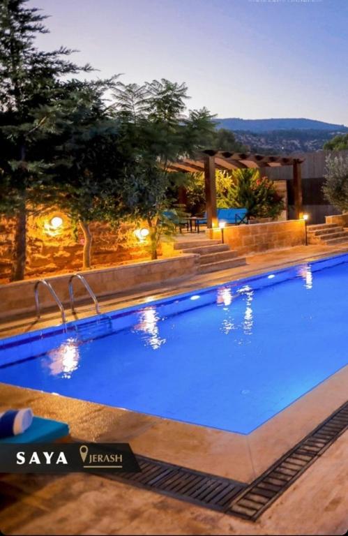a large blue swimming pool with lights on a building at Villa Saya Jerash in Jerash
