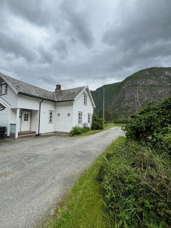 a white house on a road next to a hill at Feriehus Lærdal in Æri