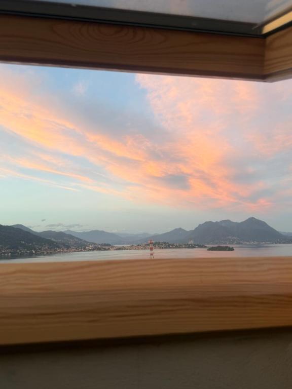a window view of a beach with a sunset at Appartamento il Punto Alto in Baveno