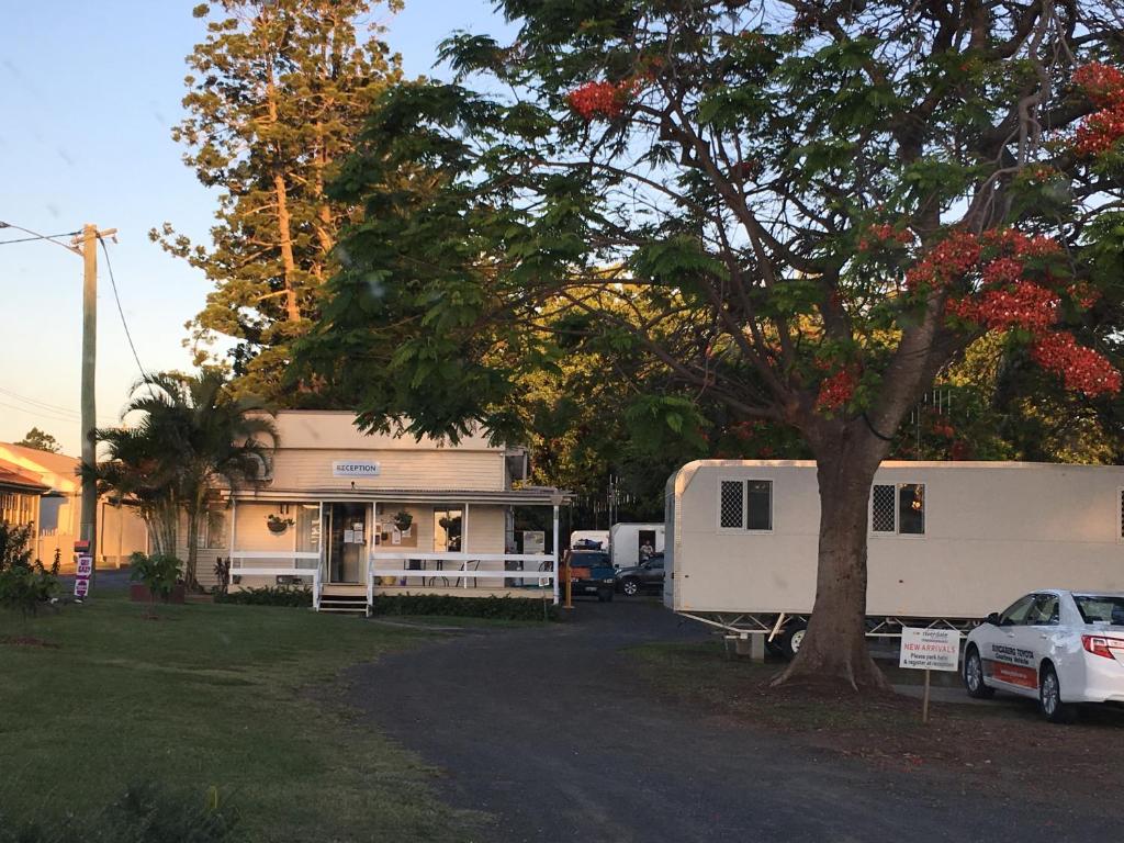 een huis met een trailer en een auto ernaast geparkeerd bij AAOK Riverdale Caravan Park in Bundaberg