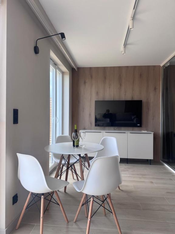 a dining room with a white table and white chairs at Diuna Apartamenty in Rowy