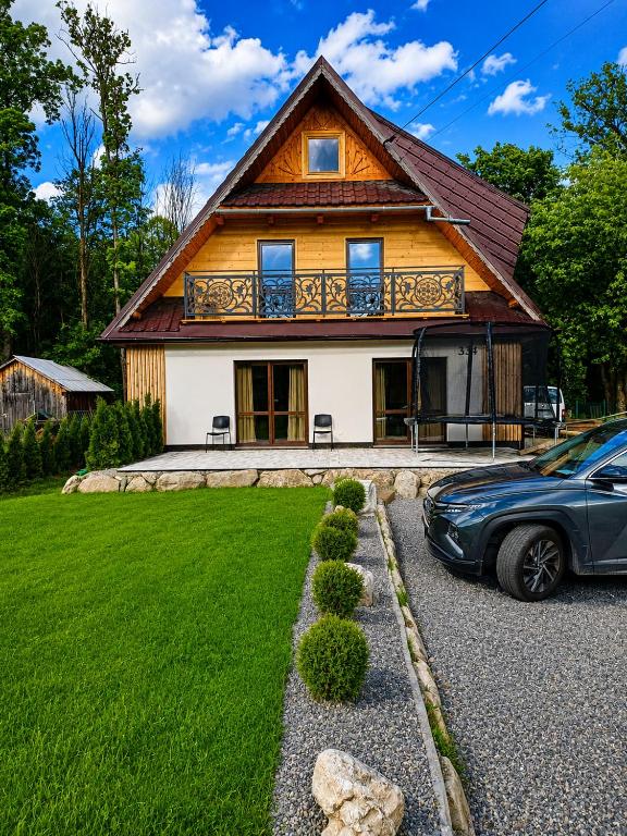 a house with a car parked in front of it at Domek u Szwajnosów in Ciche