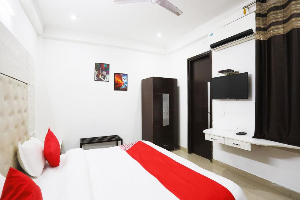 a bedroom with a white bed with red pillows at Collection O Tipsyy Inn in Gurgaon
