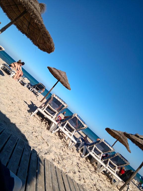 a group of chairs and umbrellas on the beach at SecretVilla in Ghār al Milḩ
