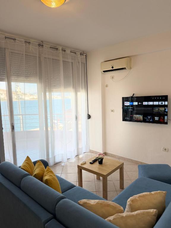 a living room with a blue couch and a table at Saranda Port View Apartments in Sarandë