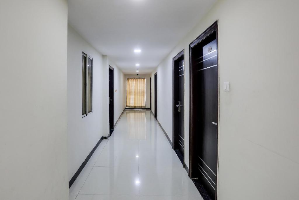a hallway with black doors and a white tile floor at Collection O Lotus Grand in Hyderabad