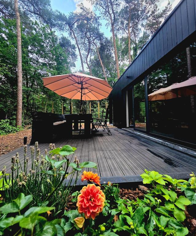 a wooden deck with a table and an umbrella at Whispering Pines in Retie