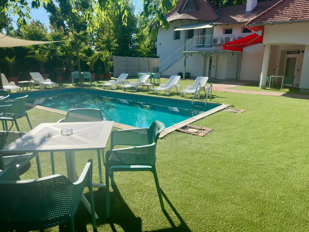 a pool with chairs and a table and a table and chairs at Hullam Rooms Siofok in Siófok