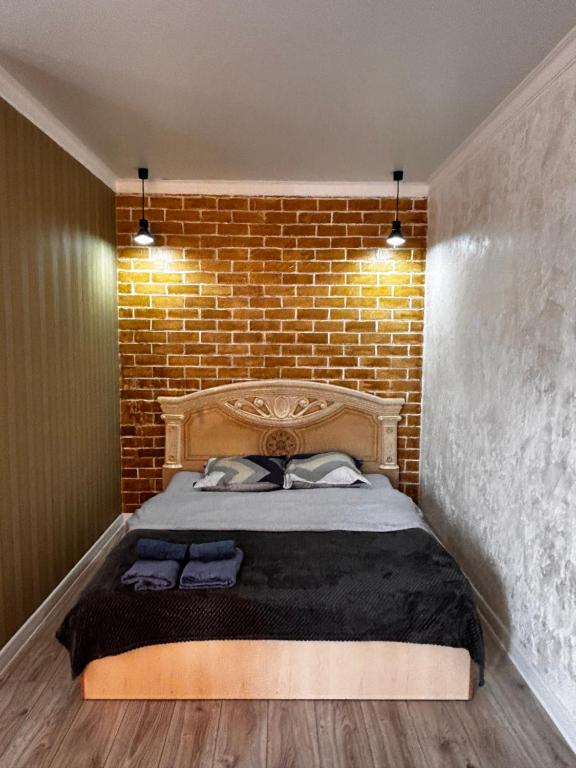 a bedroom with a bed with a brick wall at Жк сокол in Kokshetau