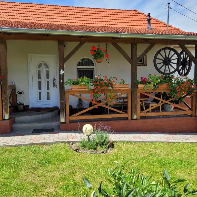 a house with a porch with flowers on it at Dom Manipura-zatrzymaj się i odpocznij w ciszy i zieleni in Muraszemenye