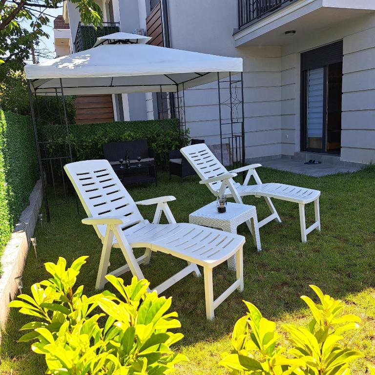 two white chairs and an umbrella on a yard at Ljubičica deluxe 2 - Novo - Privatno dvorište - Parking in Vrnjačka Banja