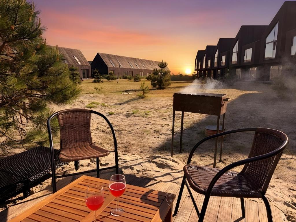 a table with two chairs and a grill with wine glasses at Sunset House Svencele in Svencelė