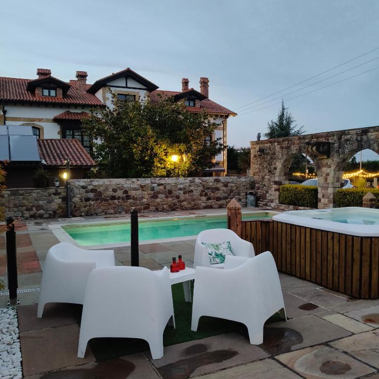 a backyard with a pool and white chairs and a table at Posada la Leyenda in Santillana del Mar
